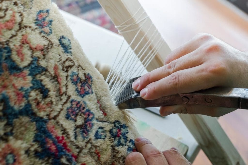 Person fixing the fringe on a rug